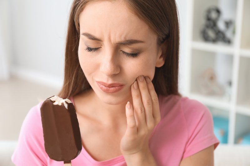 A woman suffering tooth sensitivity after eating ice cream
